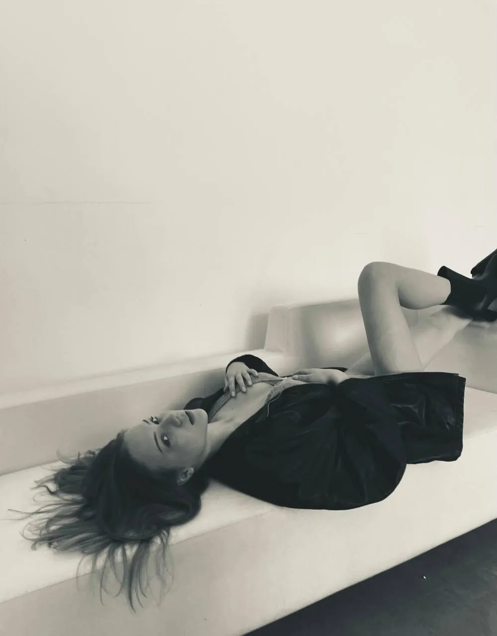 Artistic shot of a woman lying on white sofa in black dress