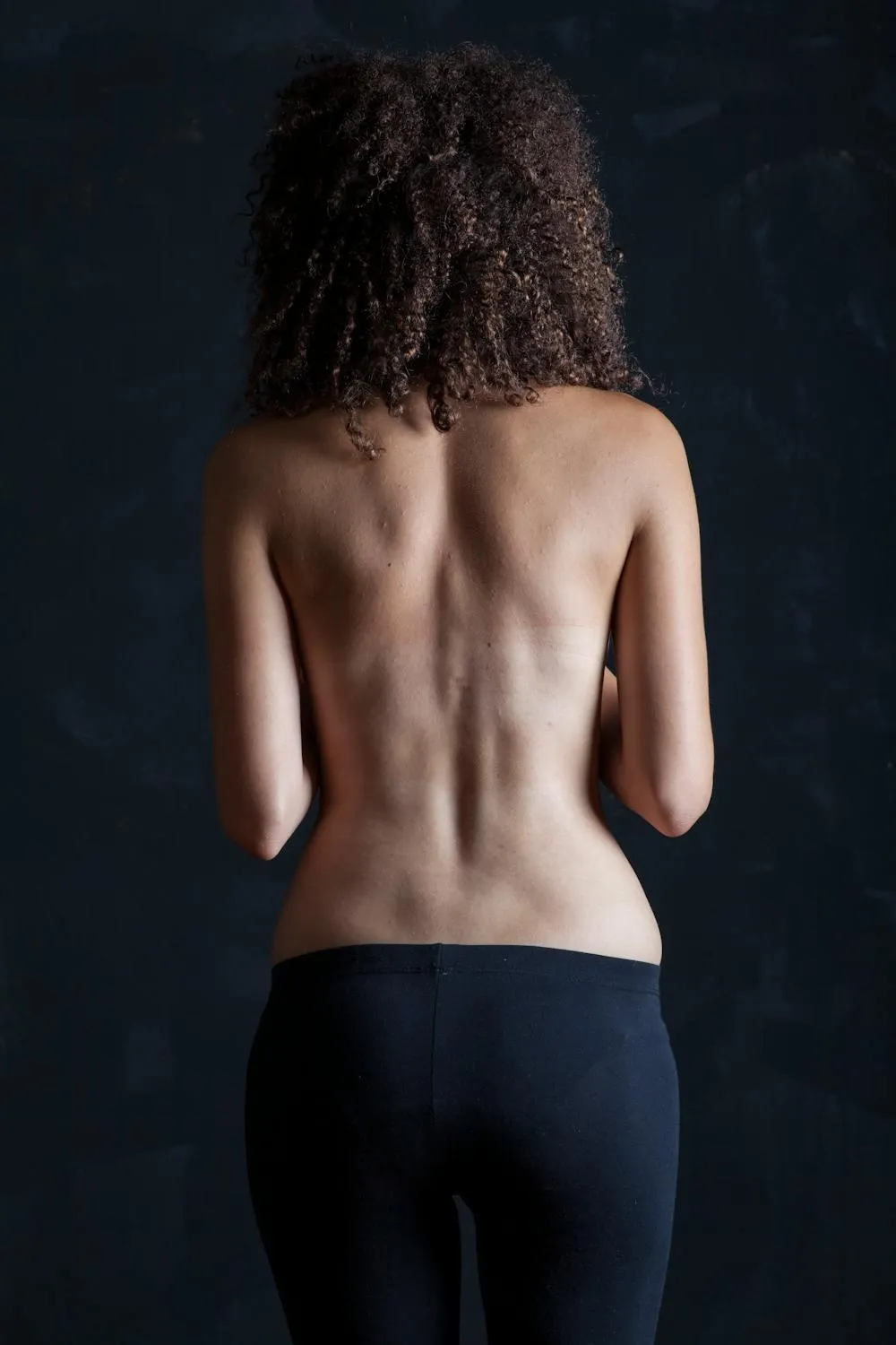 Back view of a topless woman with curly hair and jeans image