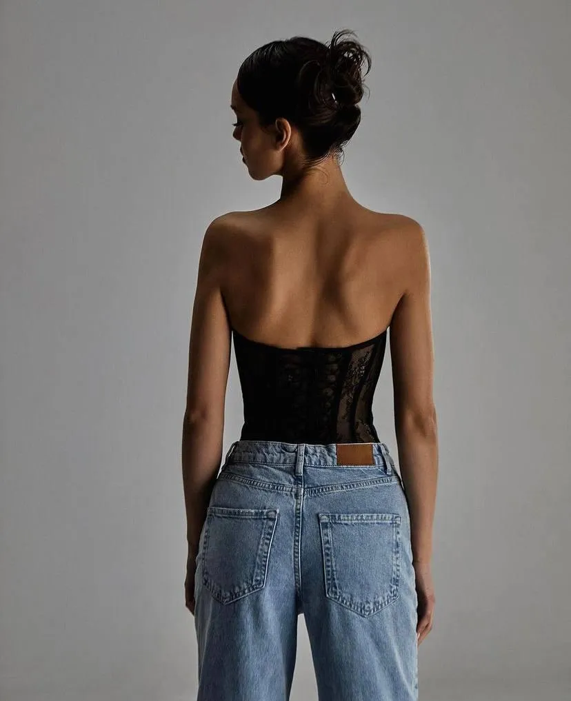 Back view of a woman in a black corset and denim jeans image