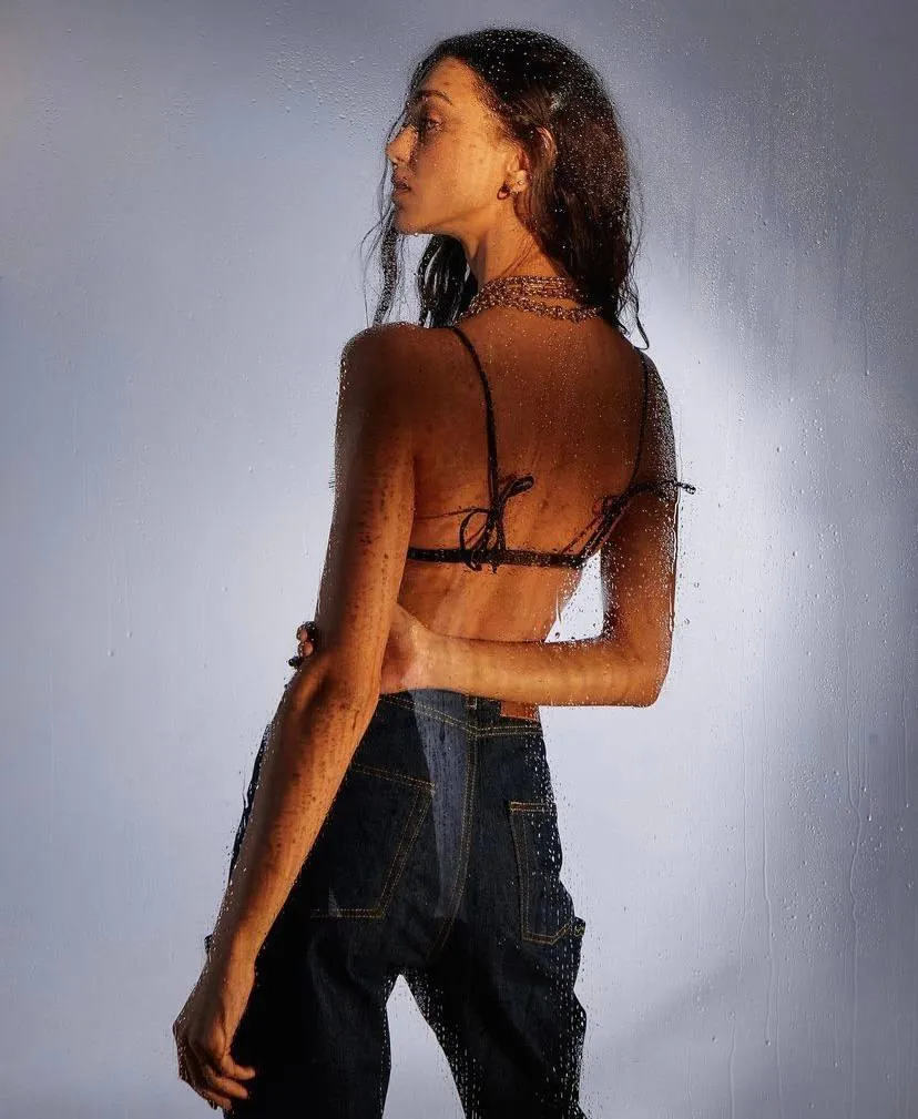 Back View of Woman in Jeans Standing Near a Soft Light Image