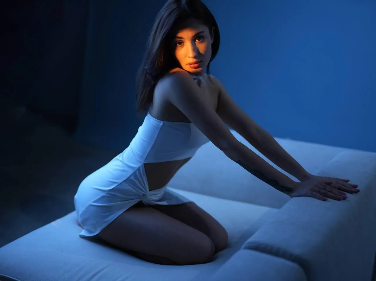 Beautiful woman sitting on the bed wearing a white dress