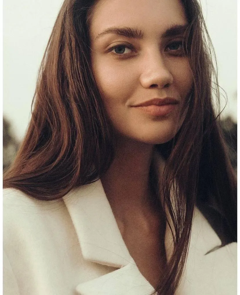 Beautiful Young Woman Smiling Gently in Cream Colored Coat