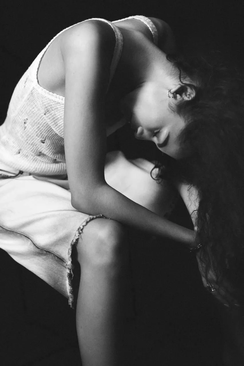 Black and white image of a woman curled up on a chair