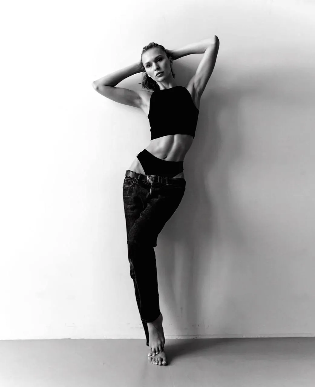 Black and white image of a woman in black crop top and jeans