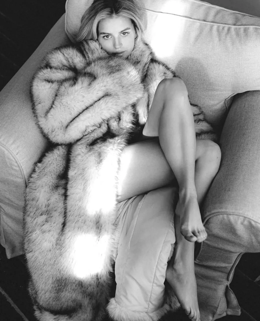 Black And White Image of a Woman Lounging in a Fur Coat