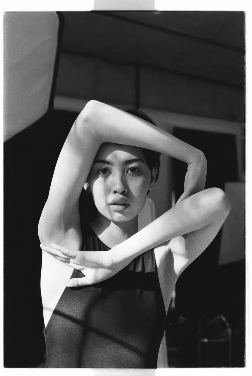 Black and white image of a woman posing with her hands up