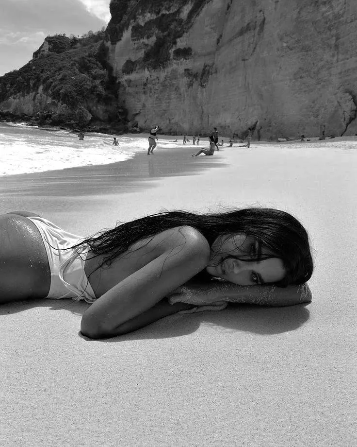 Black And White Image of Woman Lying on Beach Near Cliffs