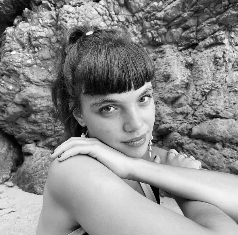 Black And White Photo of a Woman Posing by a Rocky Shoreline
