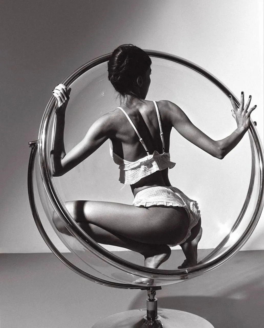 Black And White Photo of a Woman Sitting in a Circular Chair