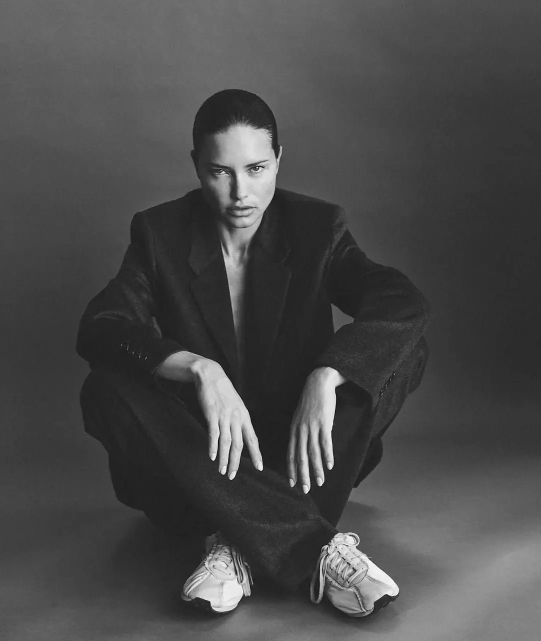 Black and white photo of woman in suit crouching and serious