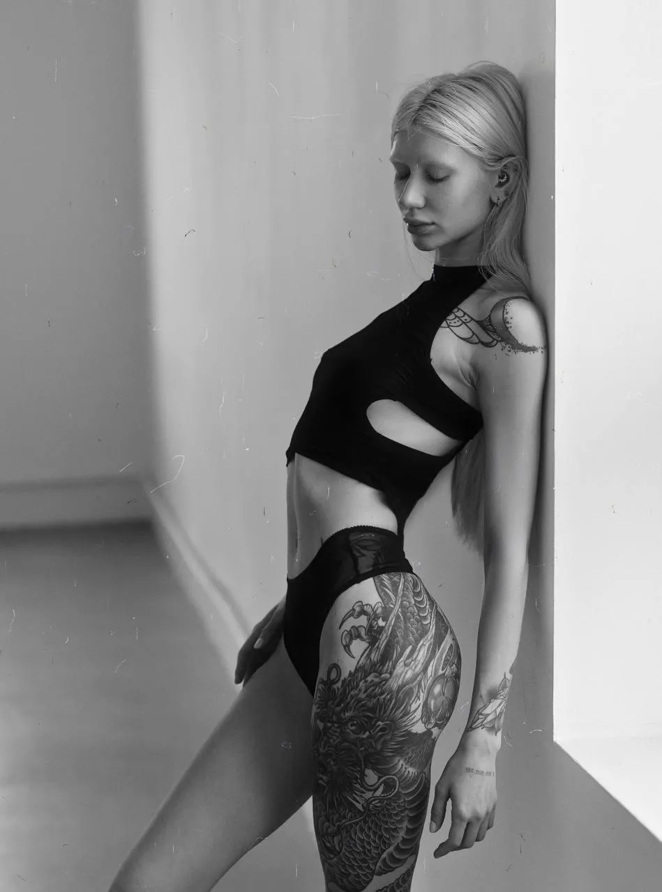 Black and white photo of woman with bold tattoos in bodysuit