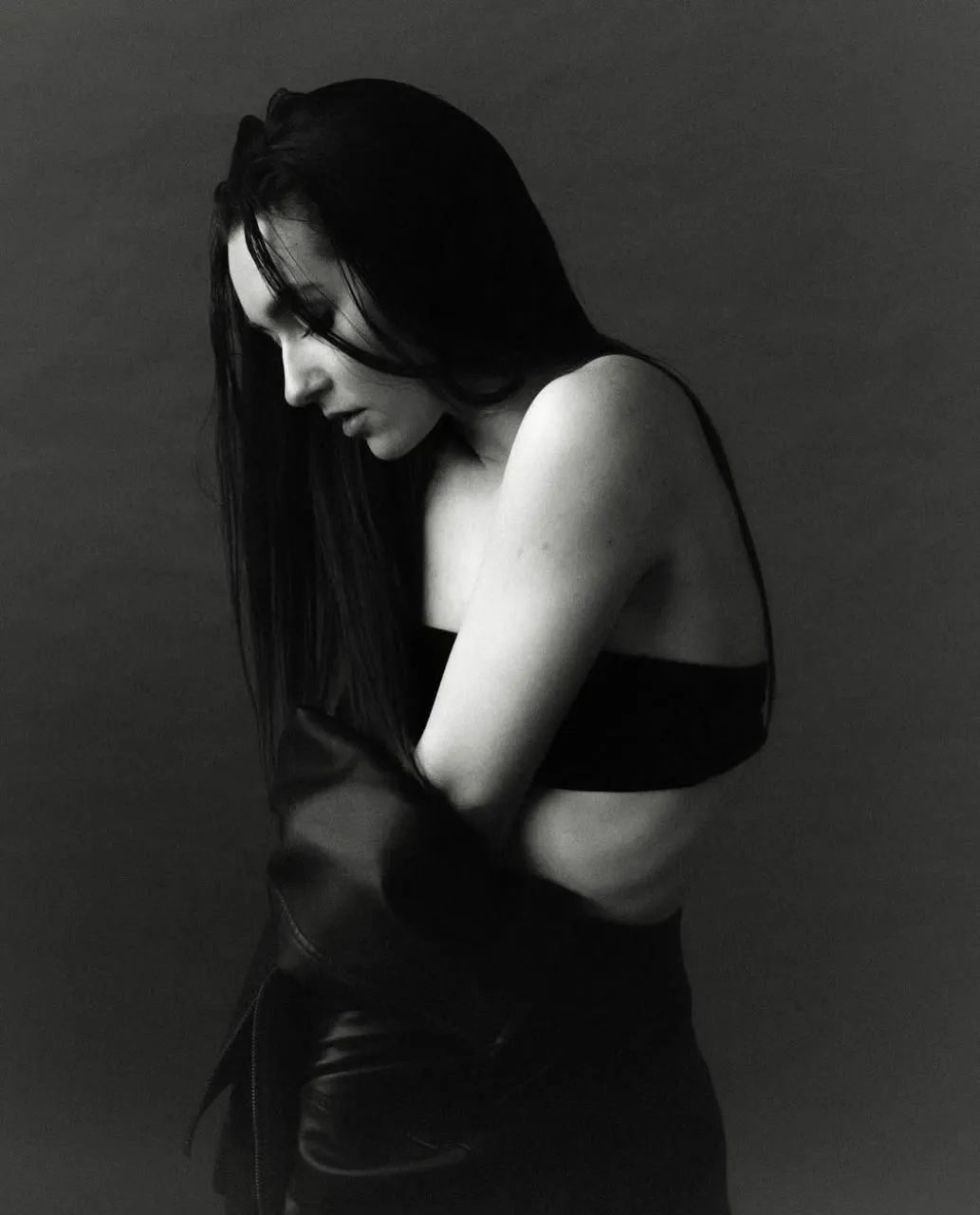 Black and white portrait of a woman hugging herself in light