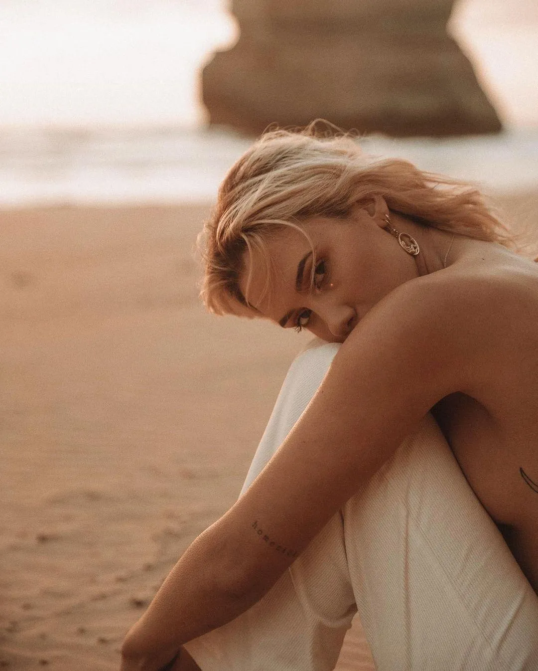 Blonde Woman in a White Dress Posing on the Sandy Seashore