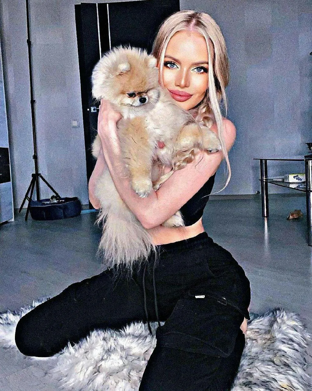 Blonde Woman Sitting with Fluffy Dog in Cozy Indoor Setting