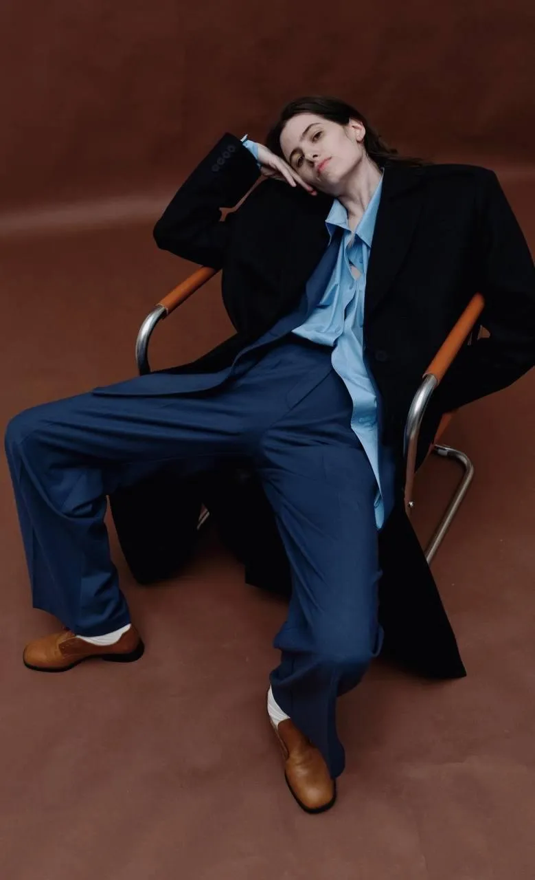 Bold young woman sitting in the leather chair free wallpaper