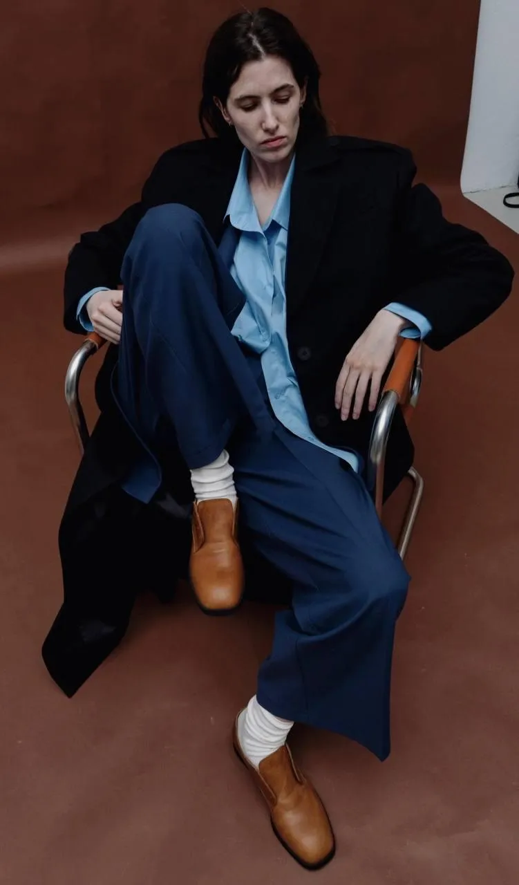 Brave woman sitting on a chair with a black coat wallpaper