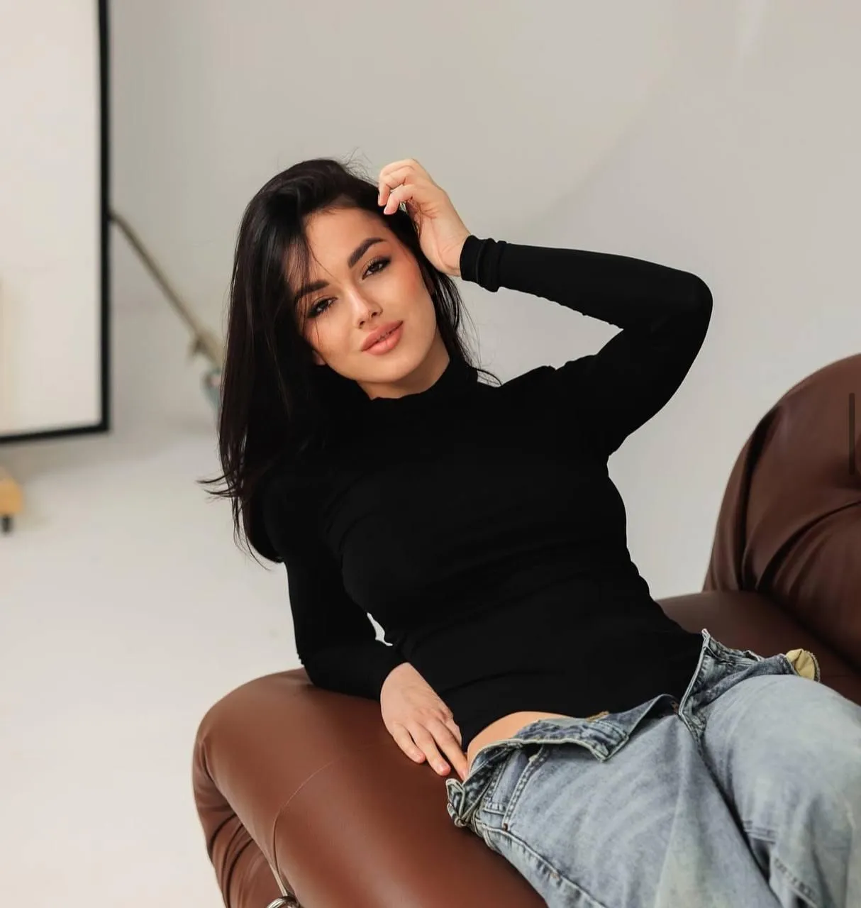 Casual woman in a black sweater and jeans sitting on a chair