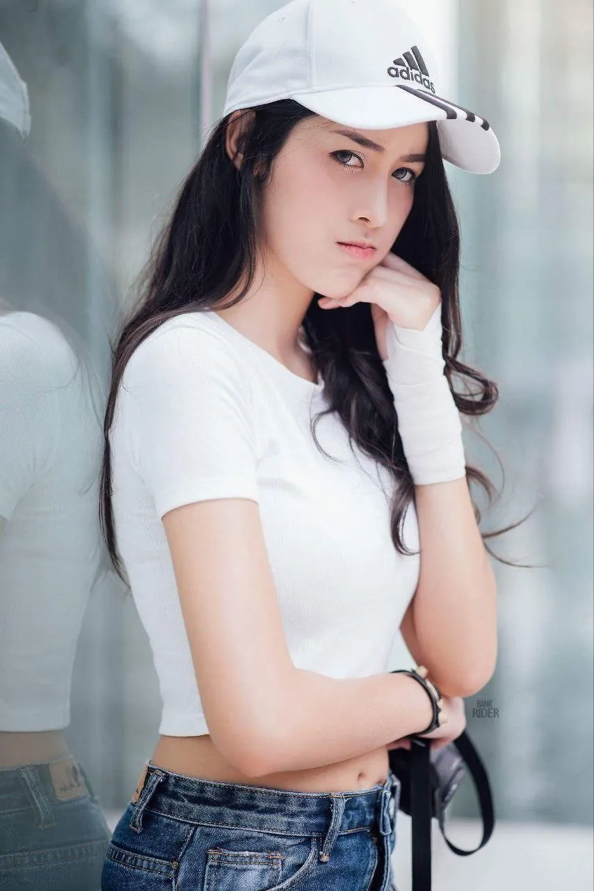 Casual Woman in Jeans And a Cap Stands Near a Glass Building