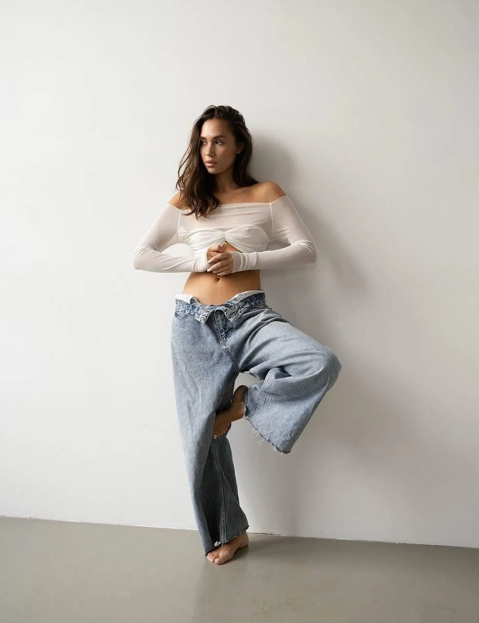 Casual woman in jeans and a white top leaning on the wall