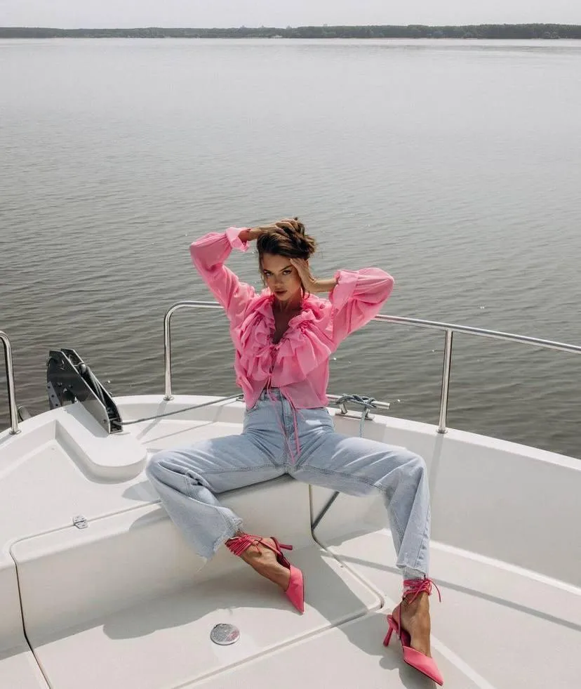 Casual woman on a boat wearing a pink jacket and denim jeans