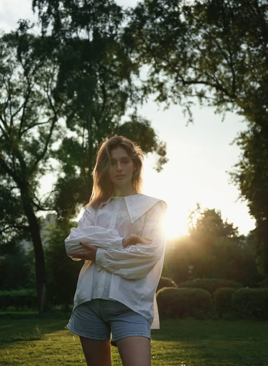 Casual Woman Standing Outdoors with Trees And Sun Shining