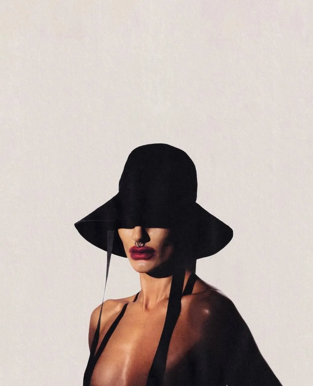 Chic Woman in Wide Brim Hat Posing Against Beige Background