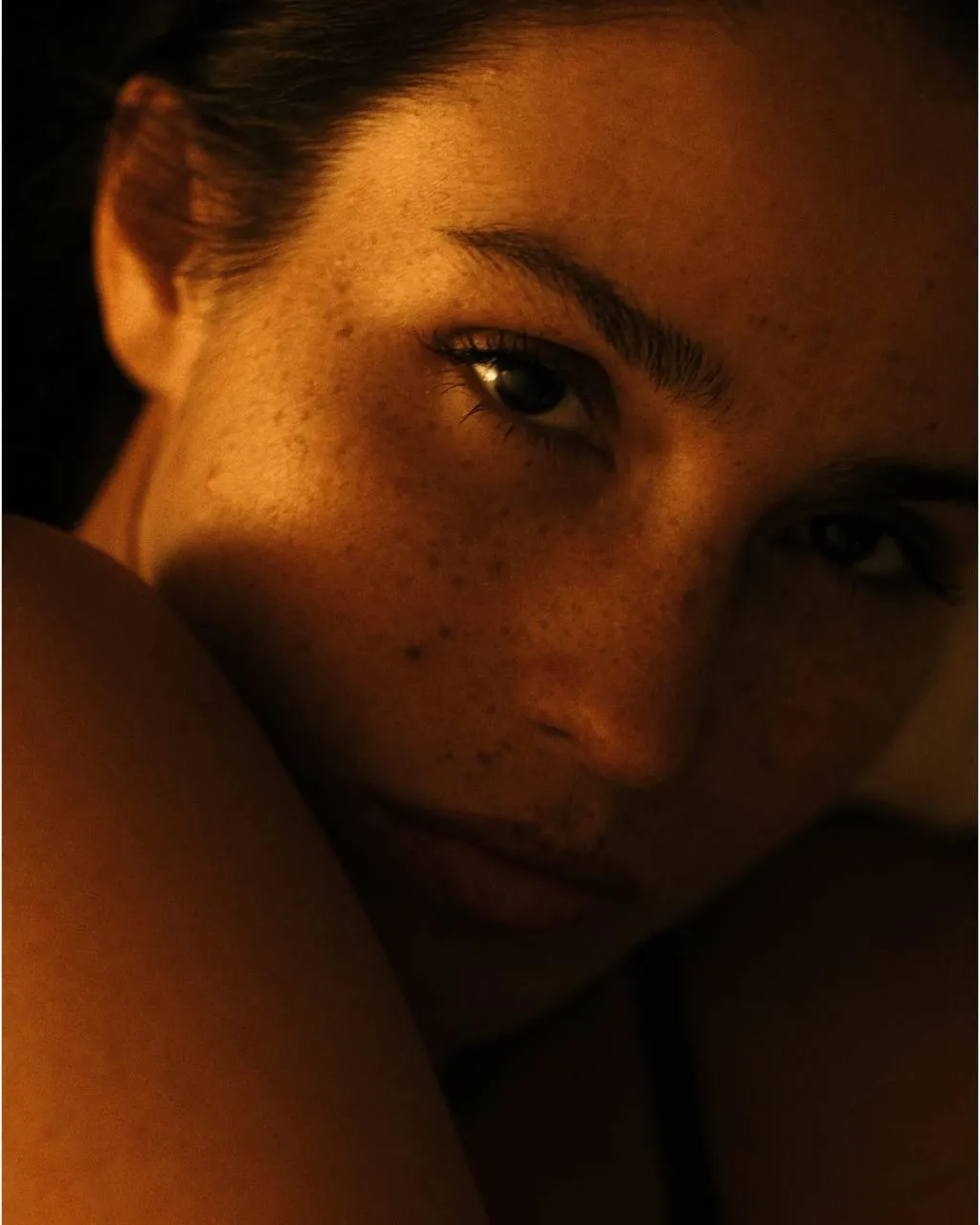 Close up of a sunlit woman with freckles and a soft smile