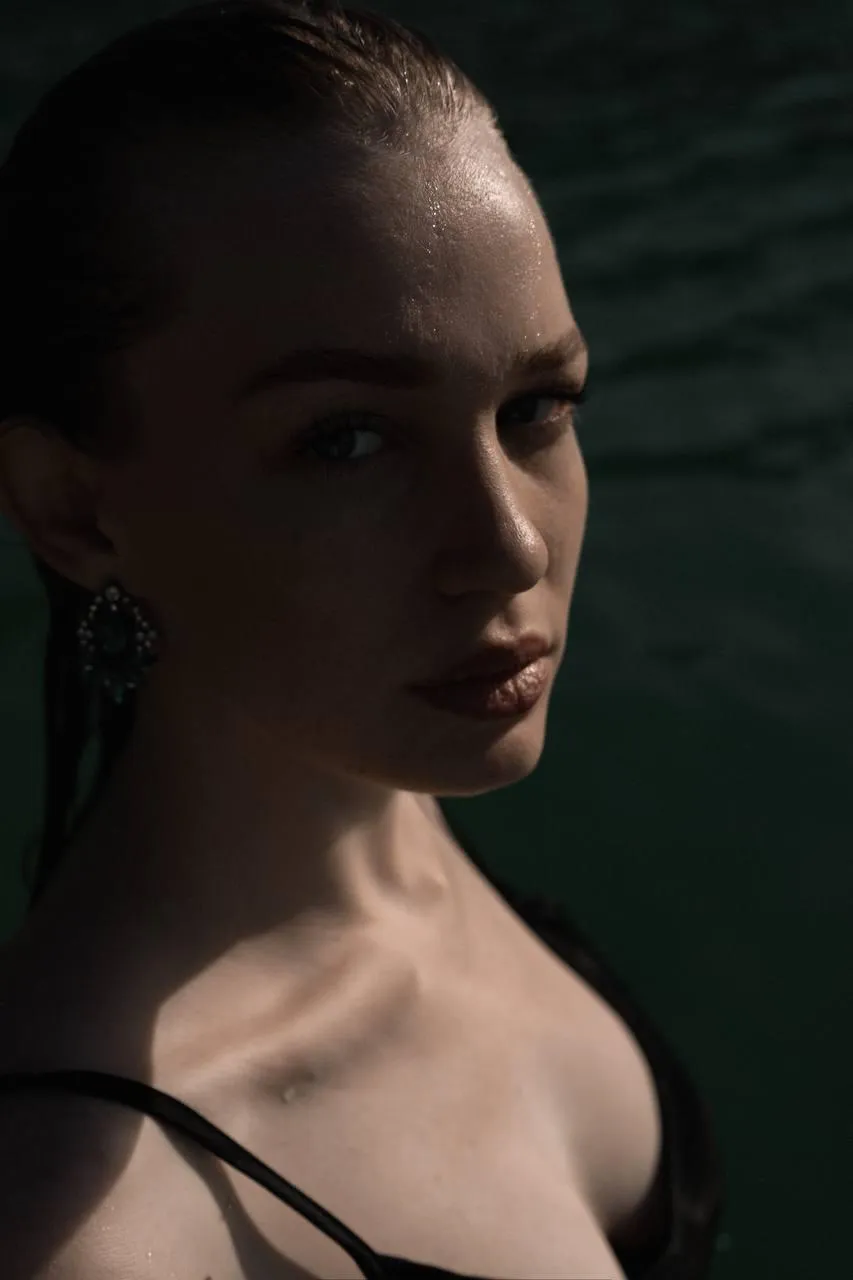 close up of a woman in a black dress near the water image
