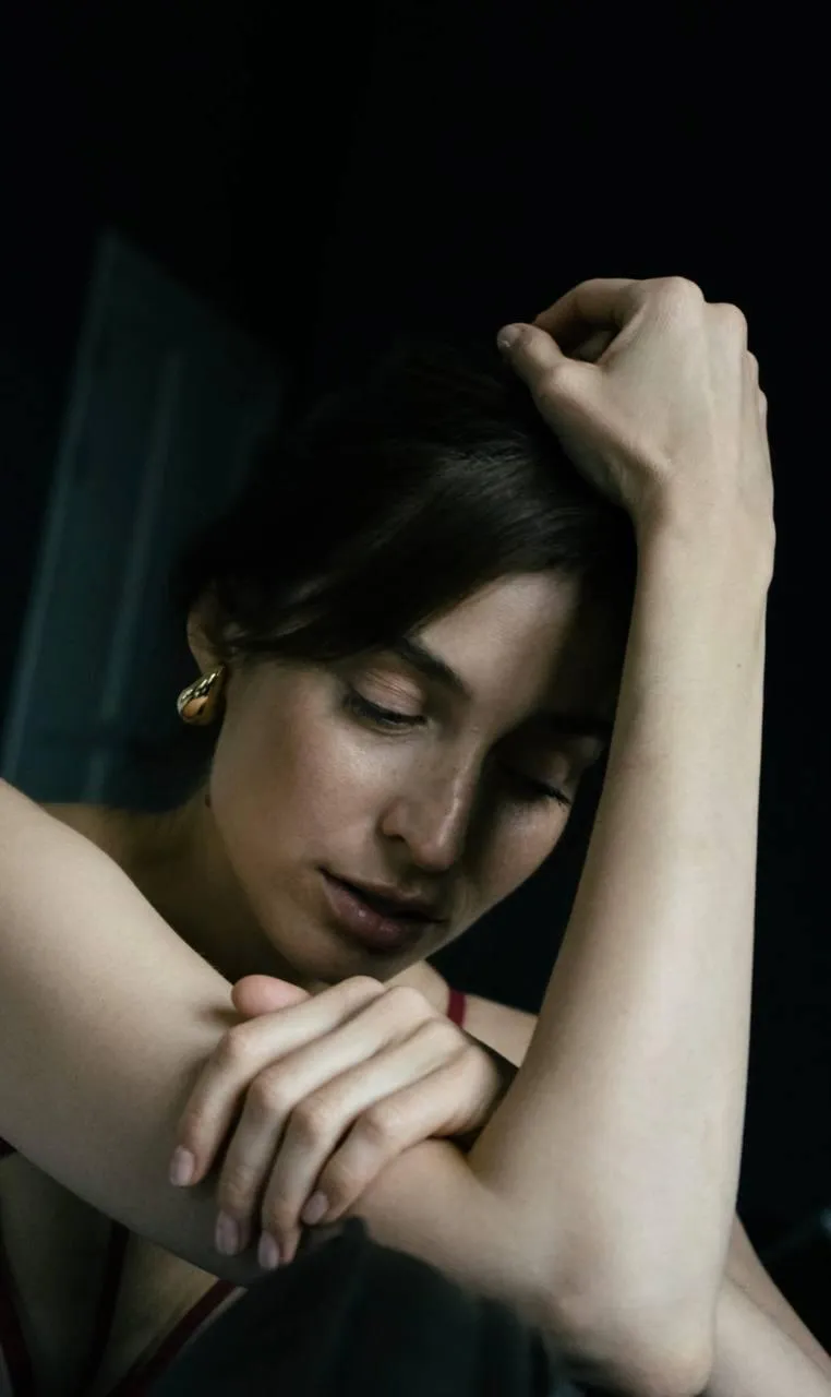 Close up of a woman sitting on black dress hand on her head