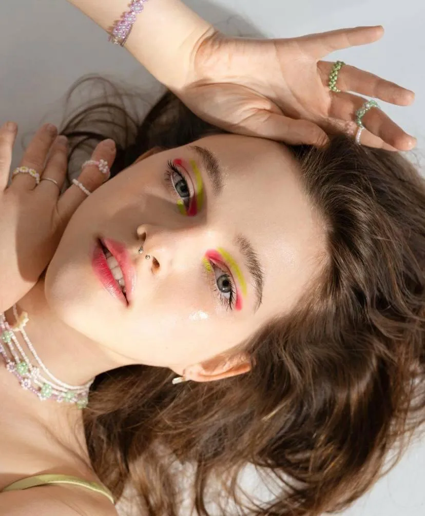 Close up of a woman with makeup and hands framing her face