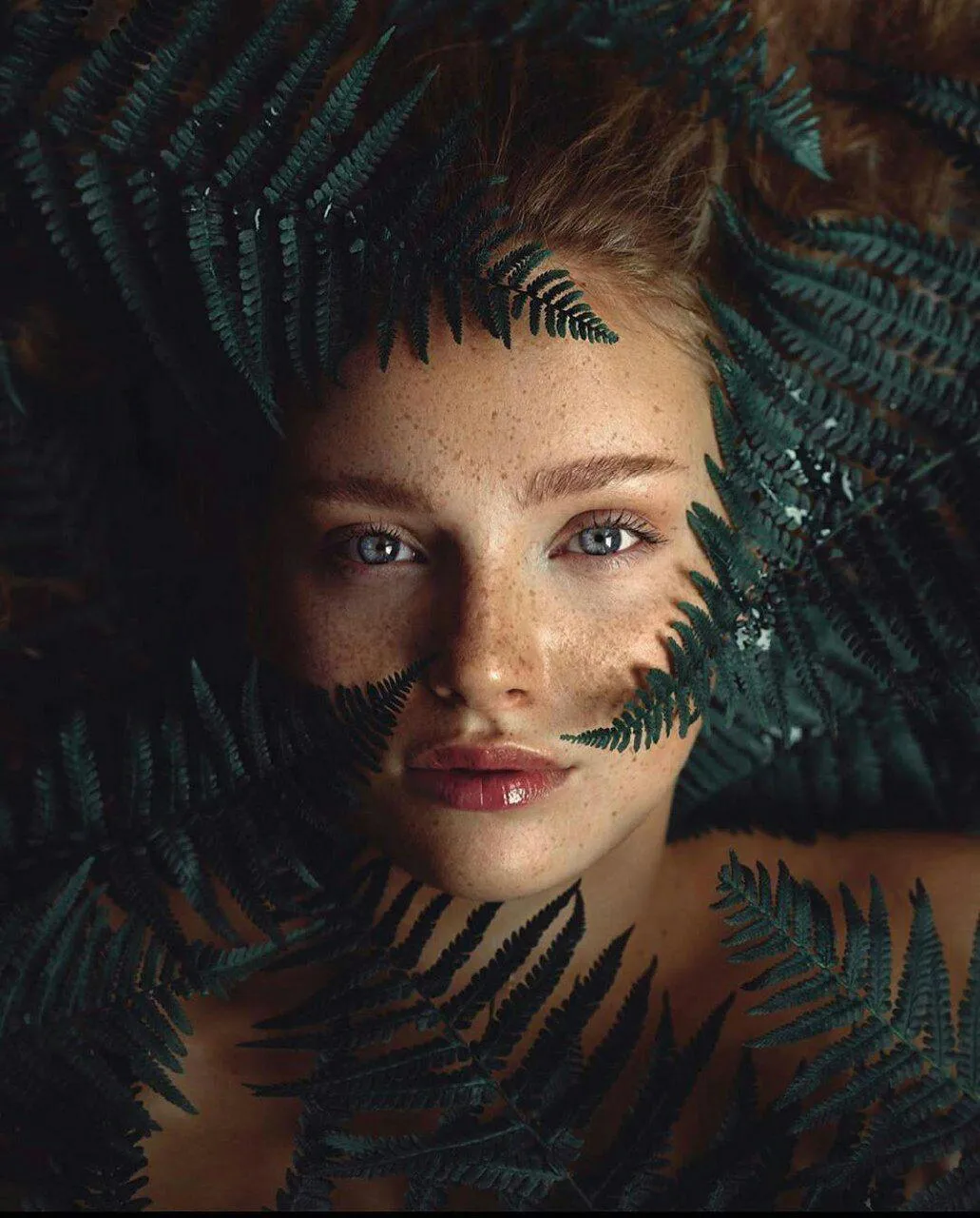 Close Up Portrait of a Woman Behind Green Tropical Leaves