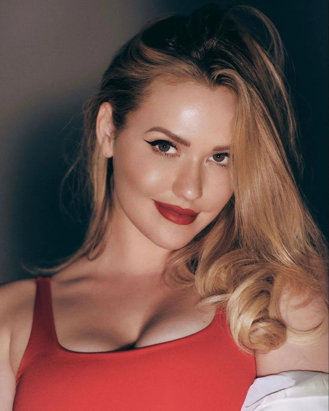 Confident Woman in a Red Top Smiling at an Evening Event