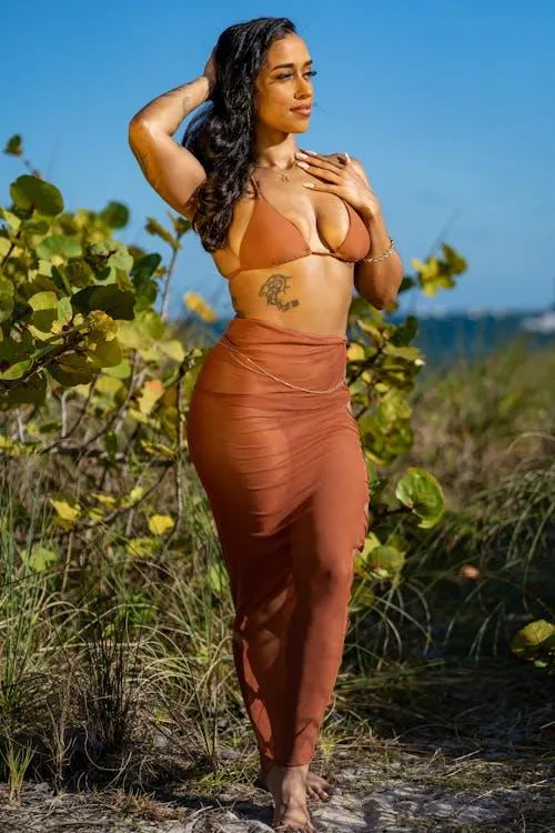 Confident woman in an orange outfit posing outdoors boldly
