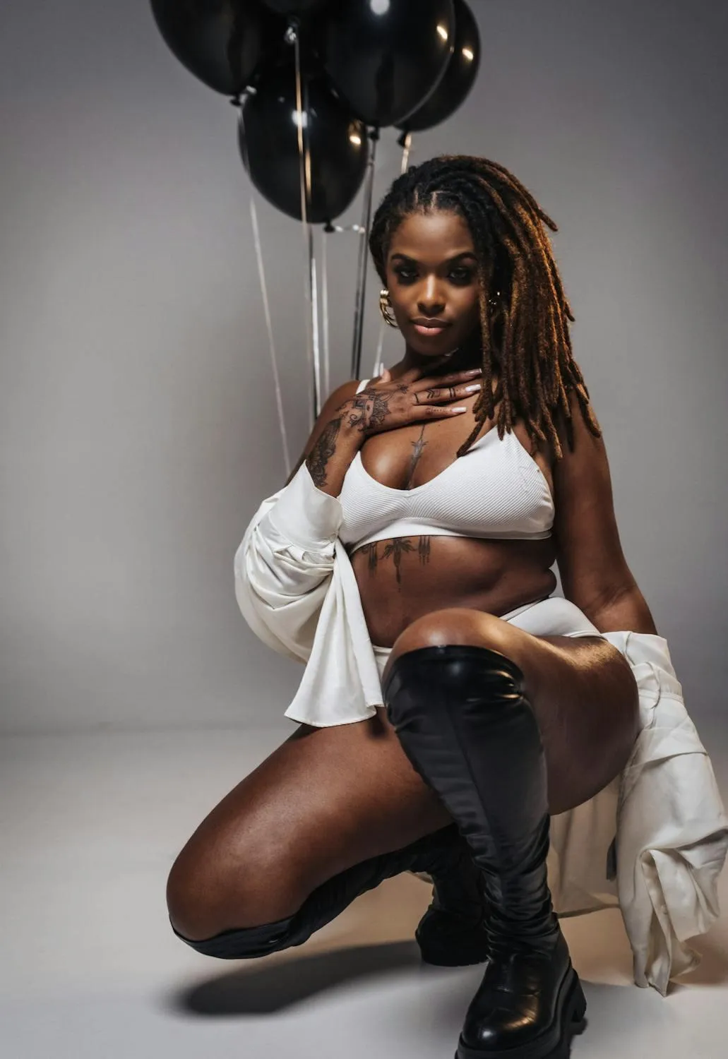 Confident Woman Poses in Black Boots And a White Crop Top