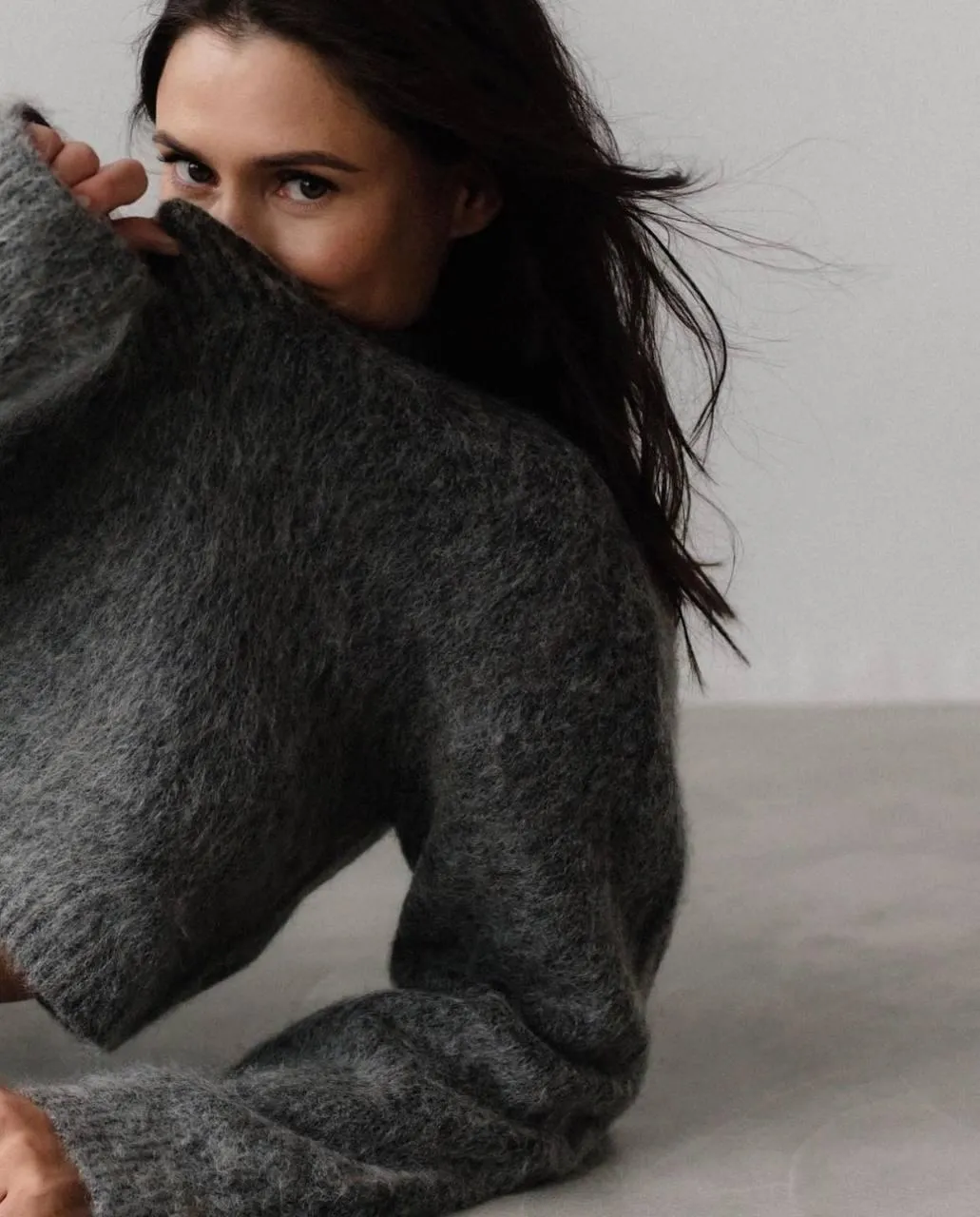 Cozy Photo of a Woman Partially Hiding Behind a Grey Sweater