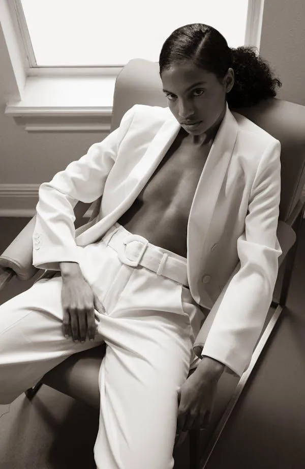 Curly hair woman in a white blazer sitting on a chair image