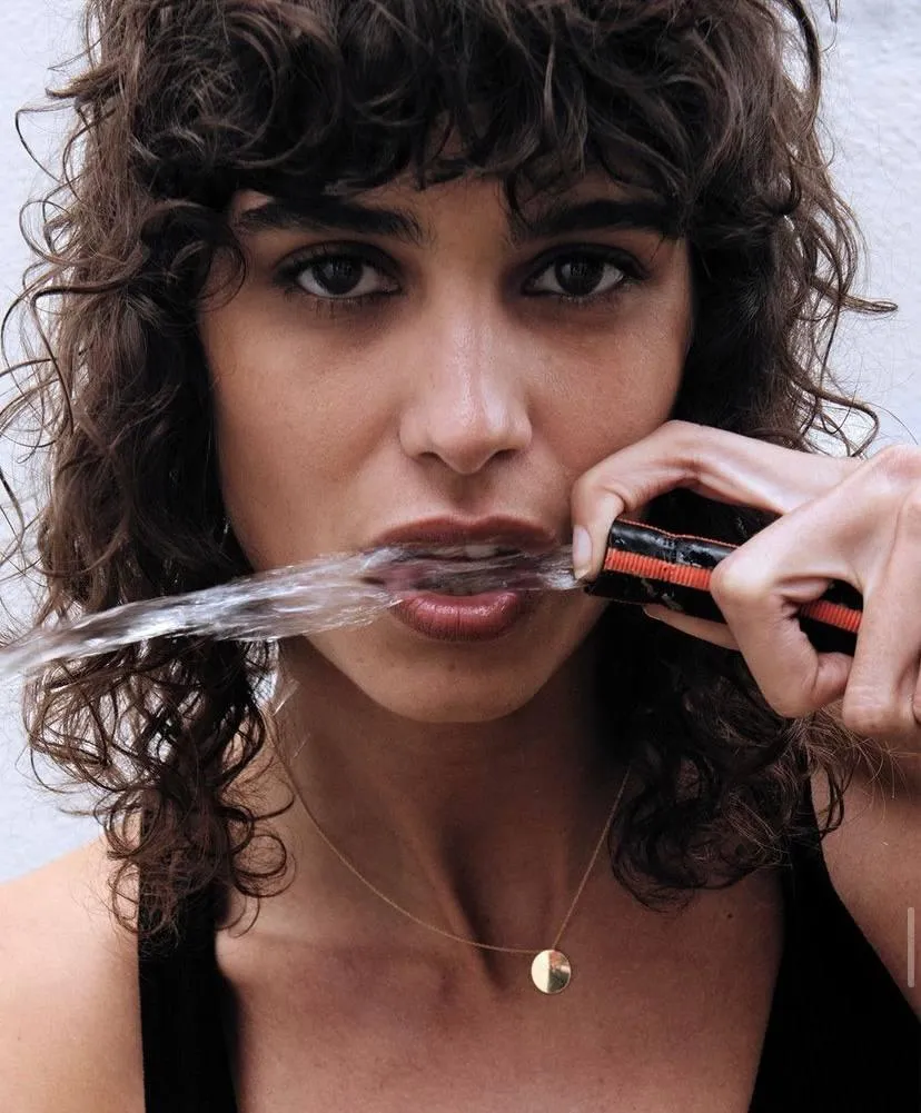 Curly Haired Model Biting Necklace in an Edgy Portrait Shoot