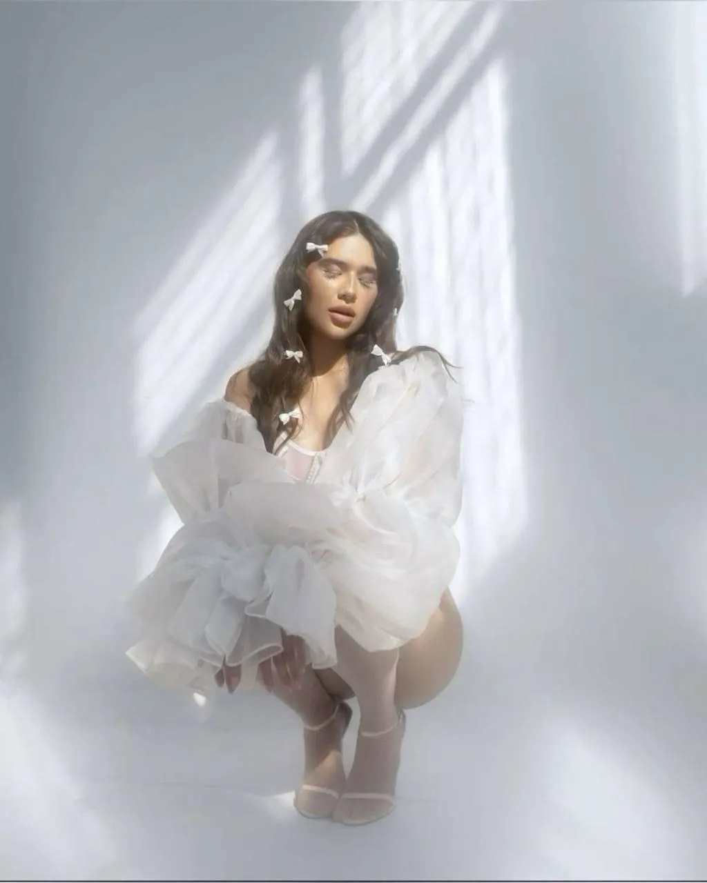 Cute woman in white squatting on the floor with eyes closed