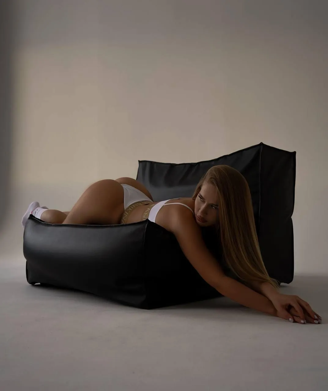 Cute woman lying on the black sofa in the studio setting