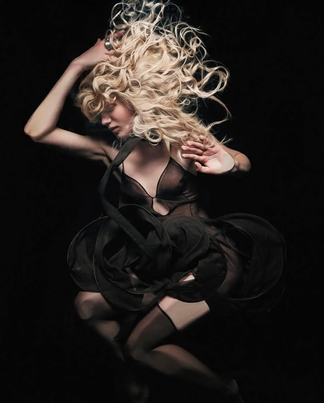 Dynamic pose of a woman with curly hair in a black dress