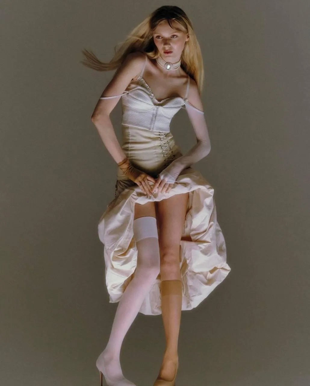 Elegant woman in a beige dress standing in a fashion pose