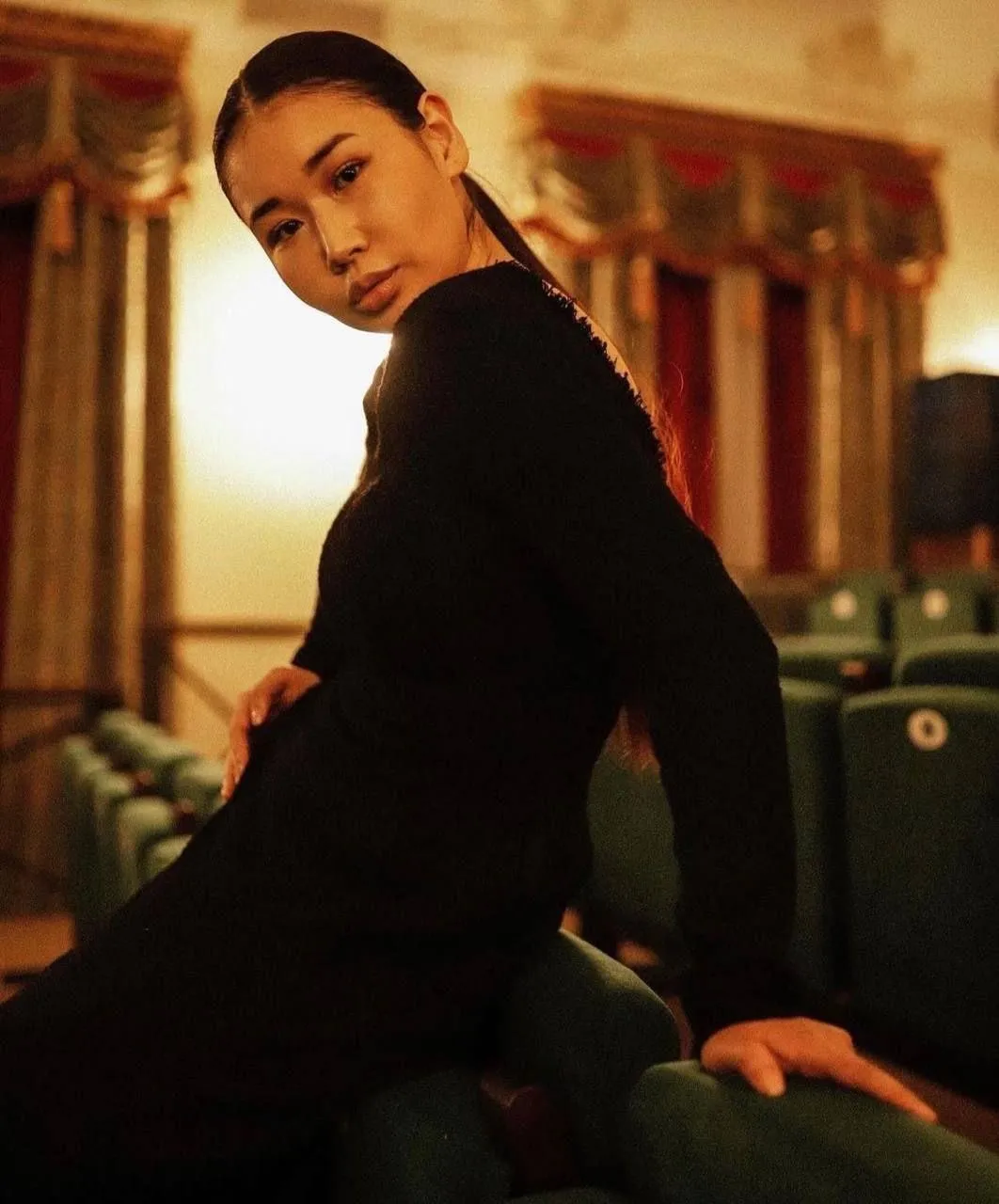 Elegant Woman in a Black Dress Leaning on a Piano Bench