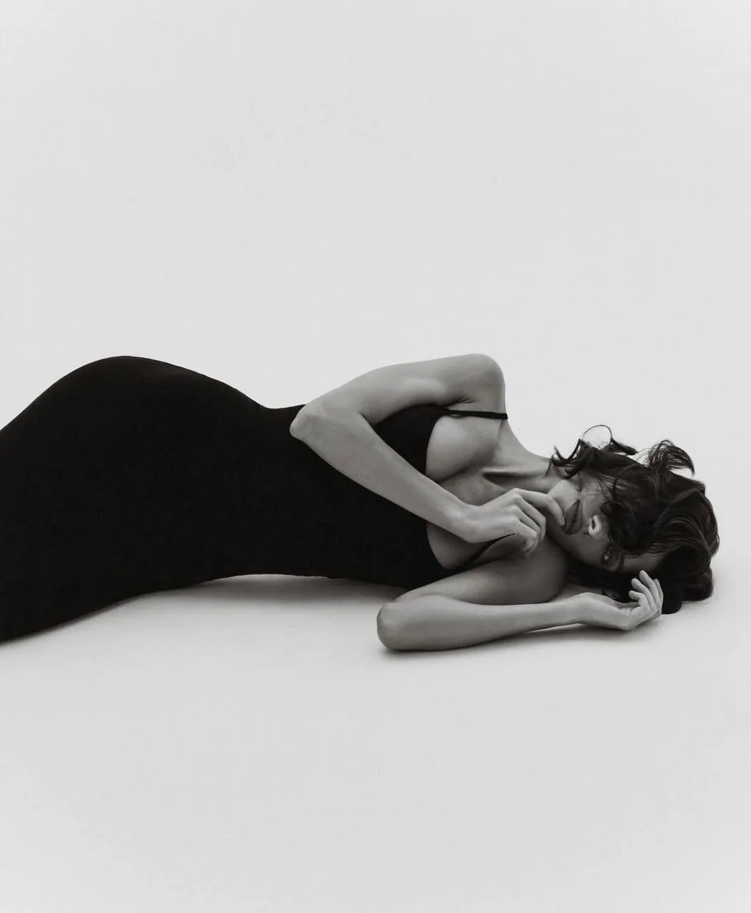 Elegant woman in a black dress reclining on the white floor