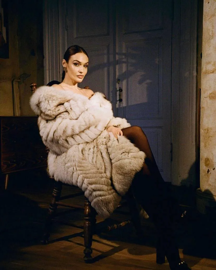 Elegant woman in a fur coat sitting on vintage wooden chair