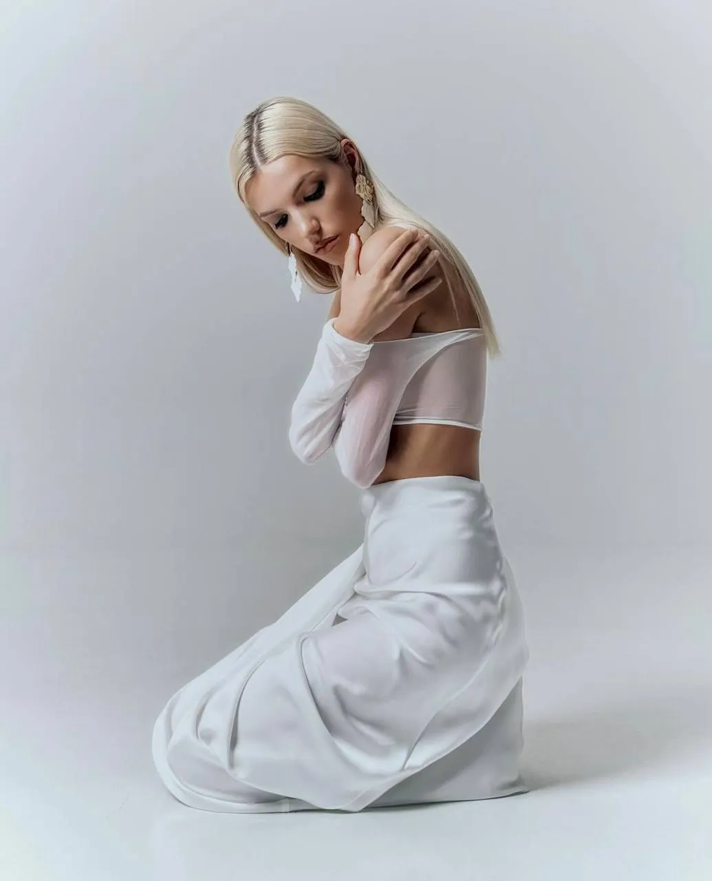 Elegant woman in a white sheer crop top and satin skirt