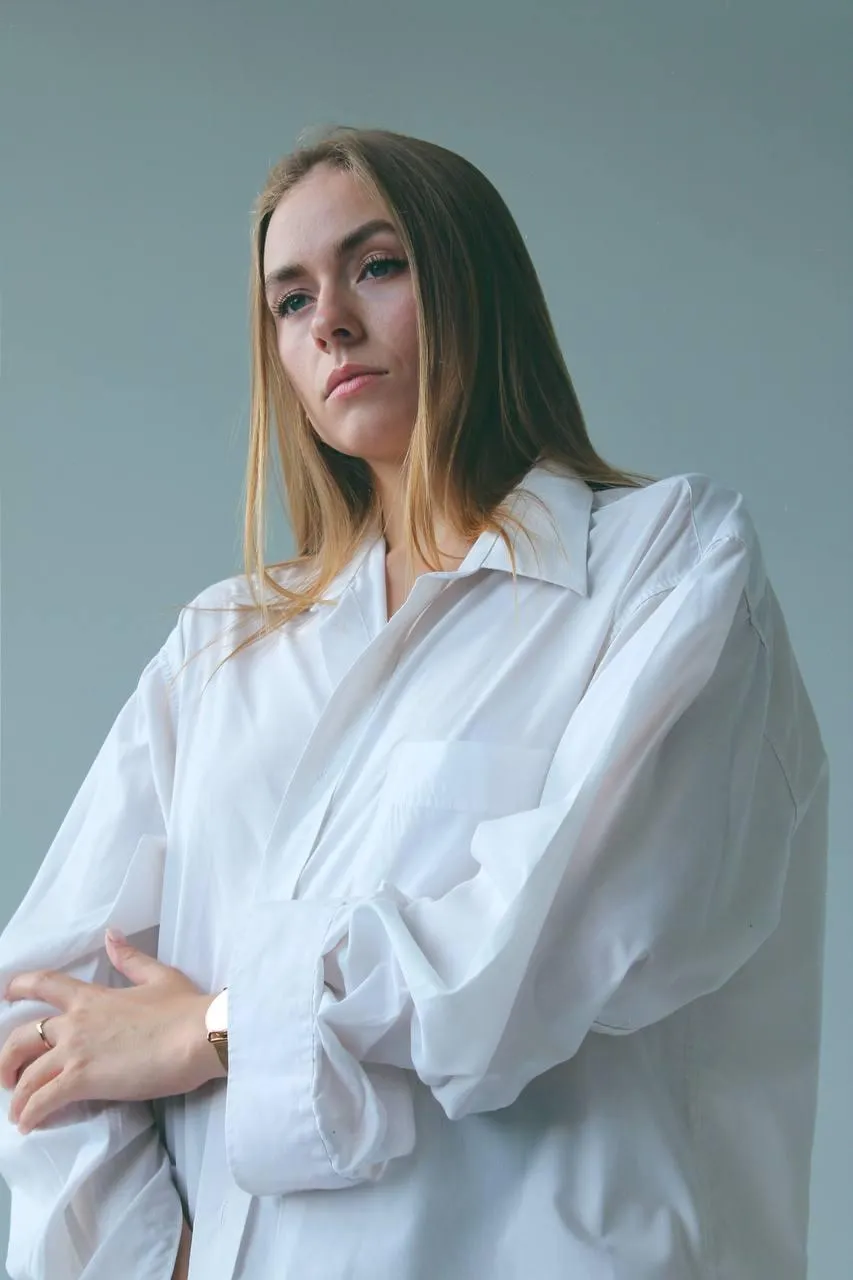Elegant woman in an oversized white shirt posing indoors