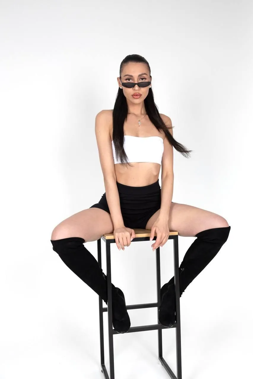 Elegant woman sitting on the stool with a crop top and boots