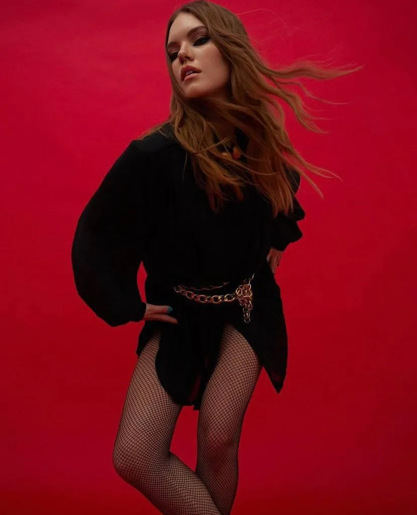 Elegant woman with long hair standing against red background