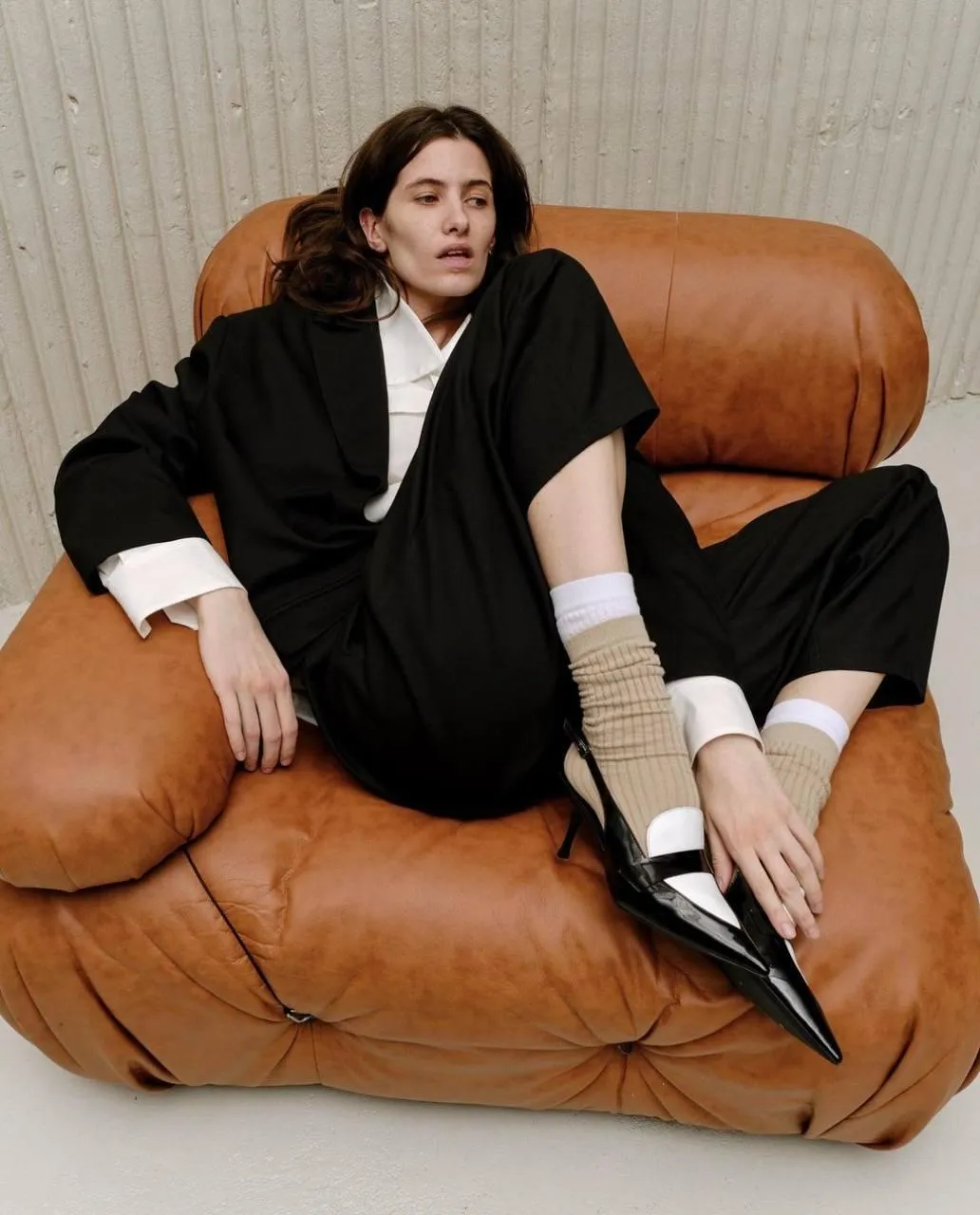 Fashion Model in Black Dress Sitting on Modern Leather Sofa