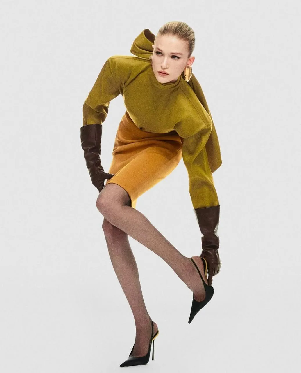 Fashion model posing in a yellow outfit on a white backdrop